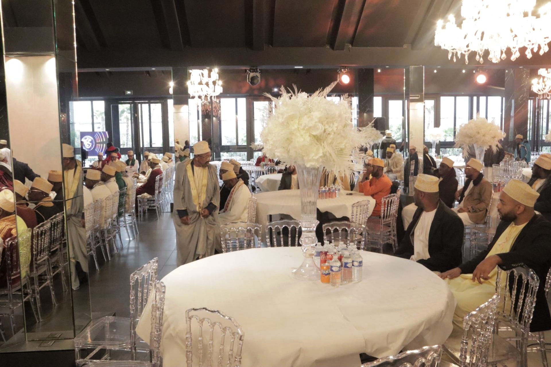 Salle de réception avec convives assis en tenue traditionnelle et kofias